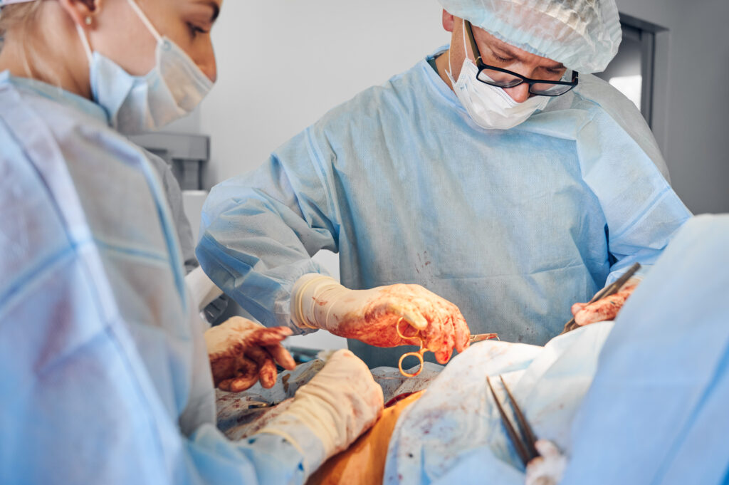surgeon and assistant conducting abdominoplasty surgery in clinic.