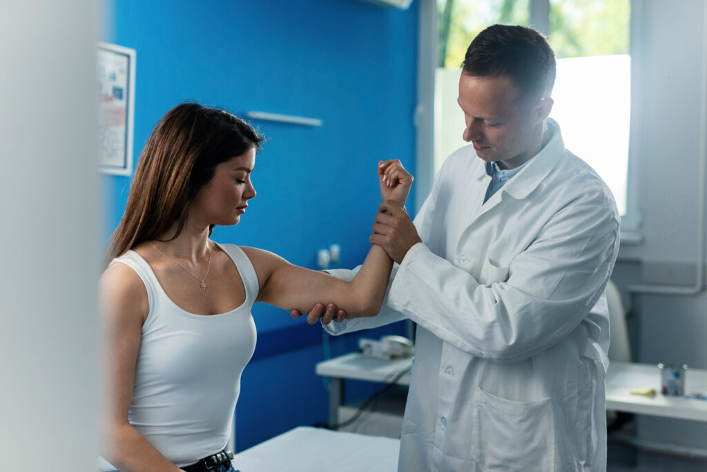 physical therapist examining arm of female patient at doctor's office.
